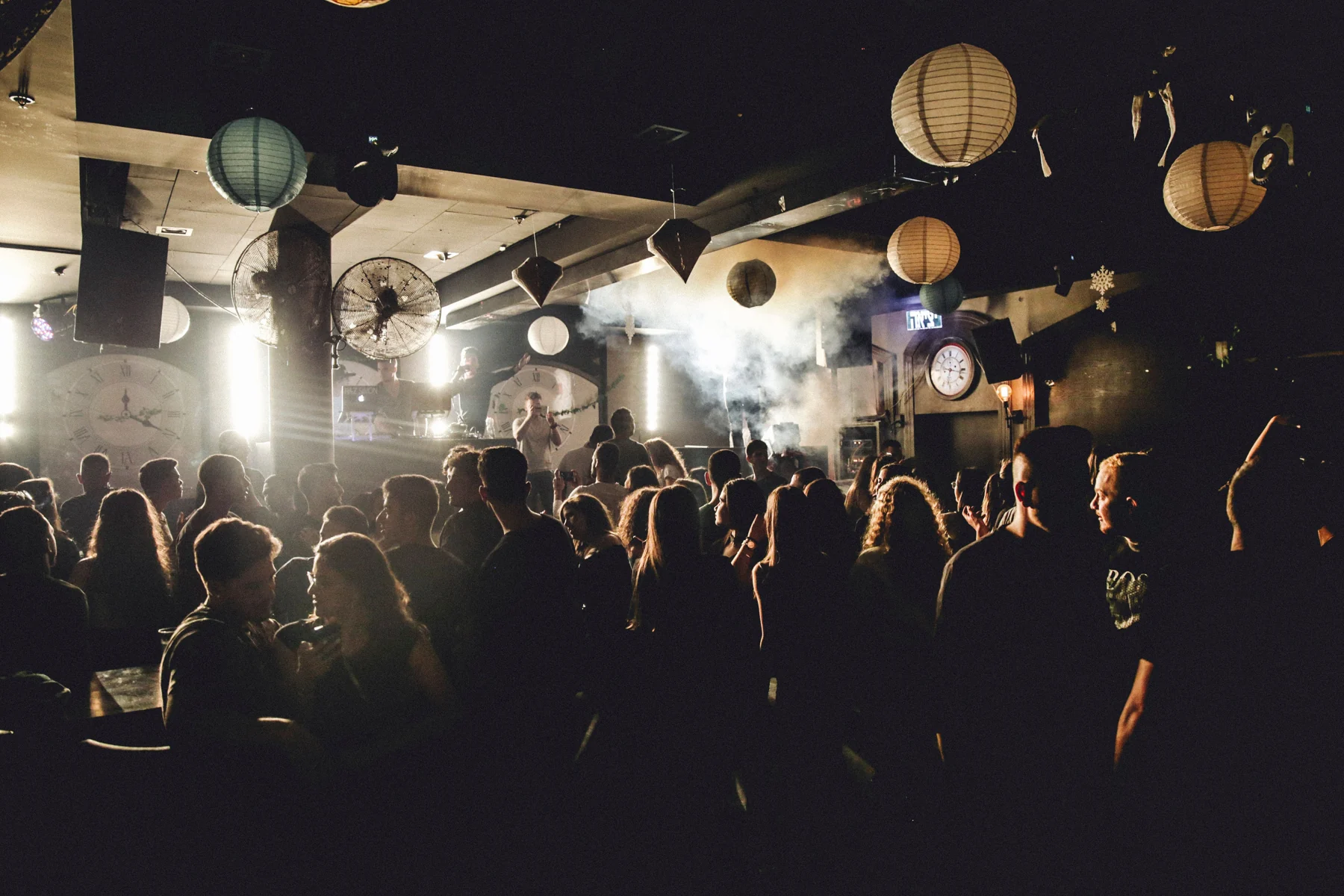 A clothed crowd gathering beneath warm lights in a nightclub
