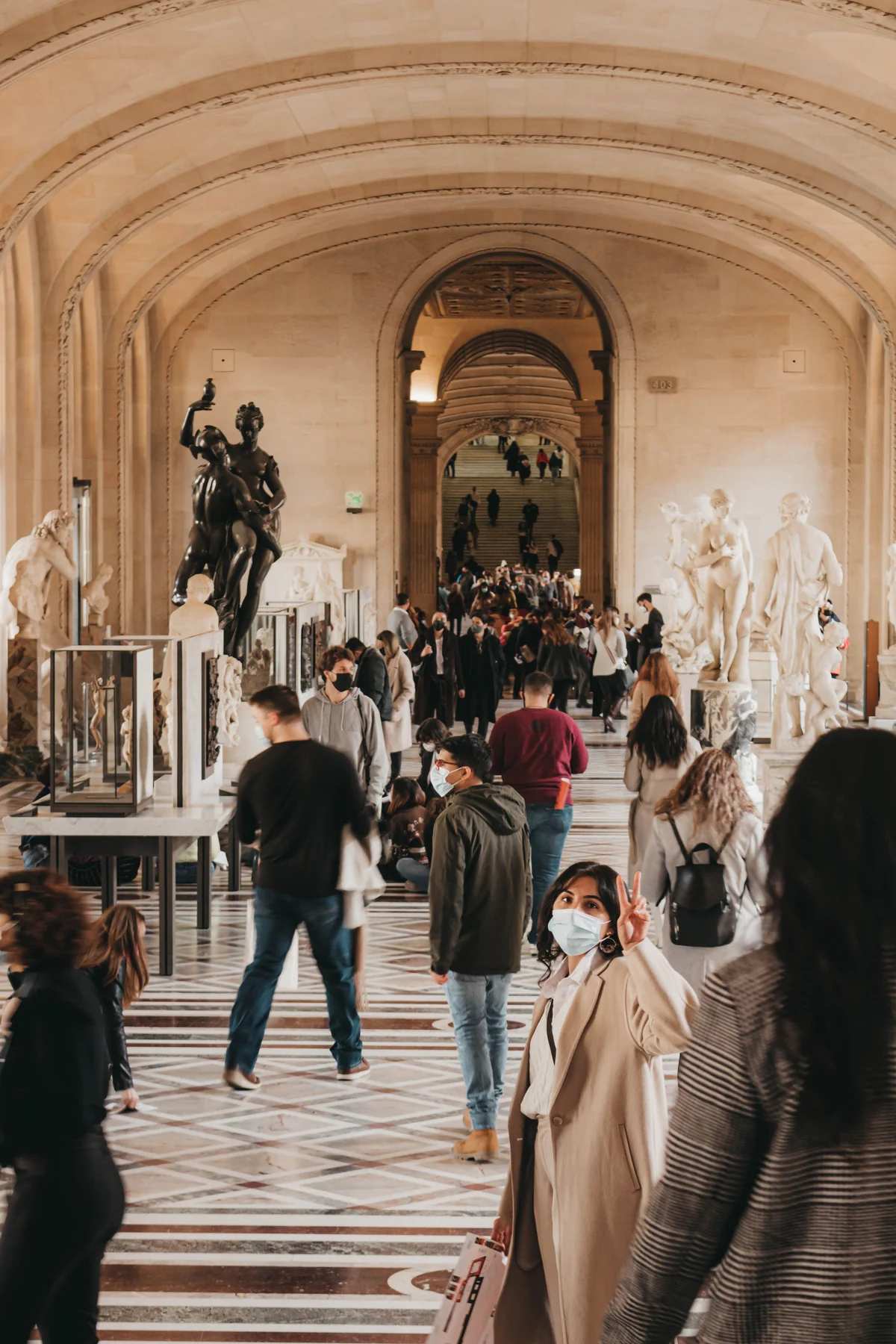 Visitors walking through a historic sculpture gallery in Paris