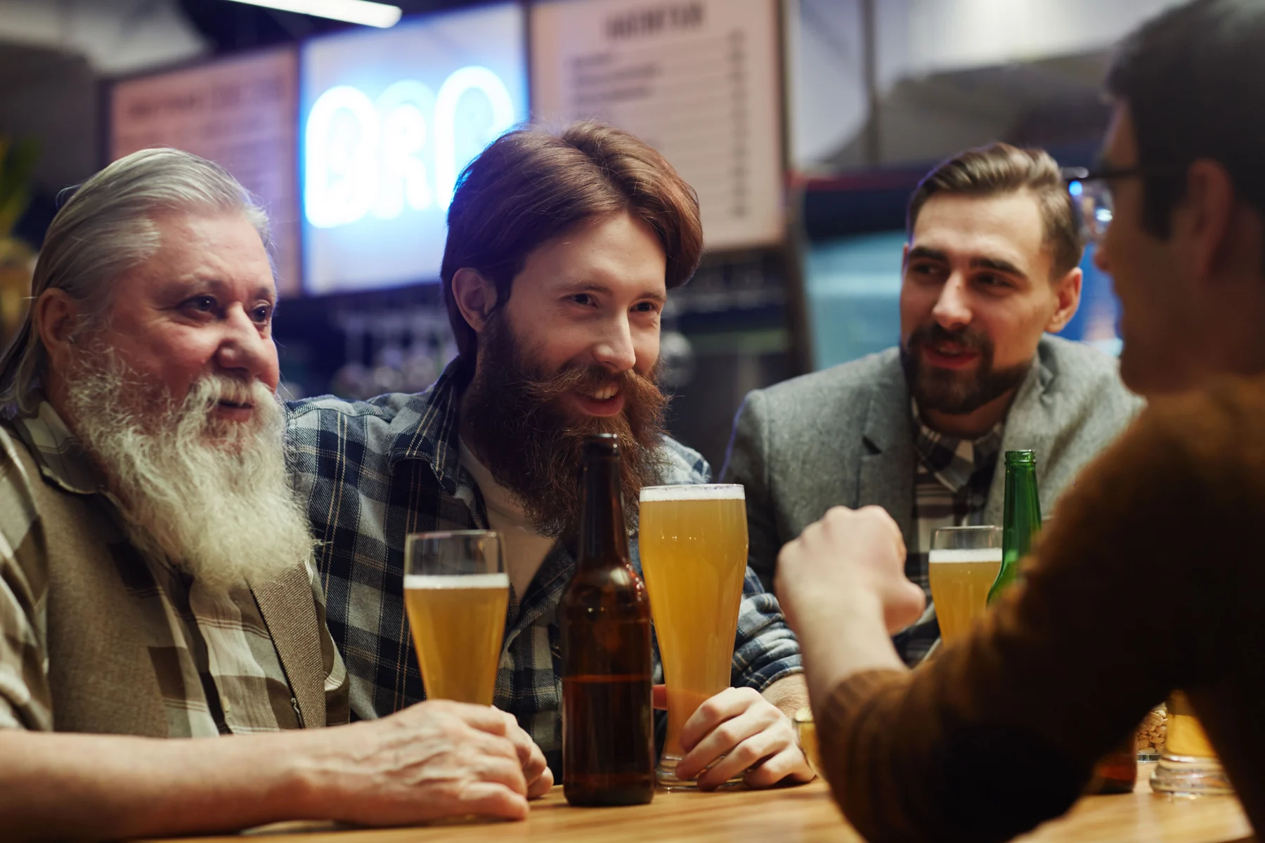 Friends in shirts and jackets sharing conversation around a bar table